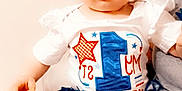 Serenity is registered to the contest to win money with this photo: baby, blanket, blue_bow, celebration, child, cute, face_paint, headband, holiday, indoor, infant, legs, patterned_clothing, person, portrait, red_white_blue, sitting, skirt, smile, white_shirt