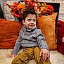 Elio joined the competition — help win amazing prizes! child, boy, sweater, pants, smiling, sitting, indoor, cushion, orange, red, flowers, pumpkins, decor, rug, cozy, portrait, happy, autumn, home, casual