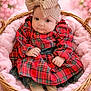 Melania is registered to the contest to win money with this photo: baby, infant, child, red_dress, plaid, headband, bow, basket, pink, soft_blanket, cozy, portrait, cute, smiling, indoors, floral_background, toddler, hands, feet, fashion
