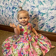 Zoey joined the competition — help win amazing prizes! toddler, child, smiling, dress, floral_pattern, carpet, indoor, wallpaper, colorful, happy, sitting, person, baby, hair_tie, cute, floor, portrait, young_child, casual, playful