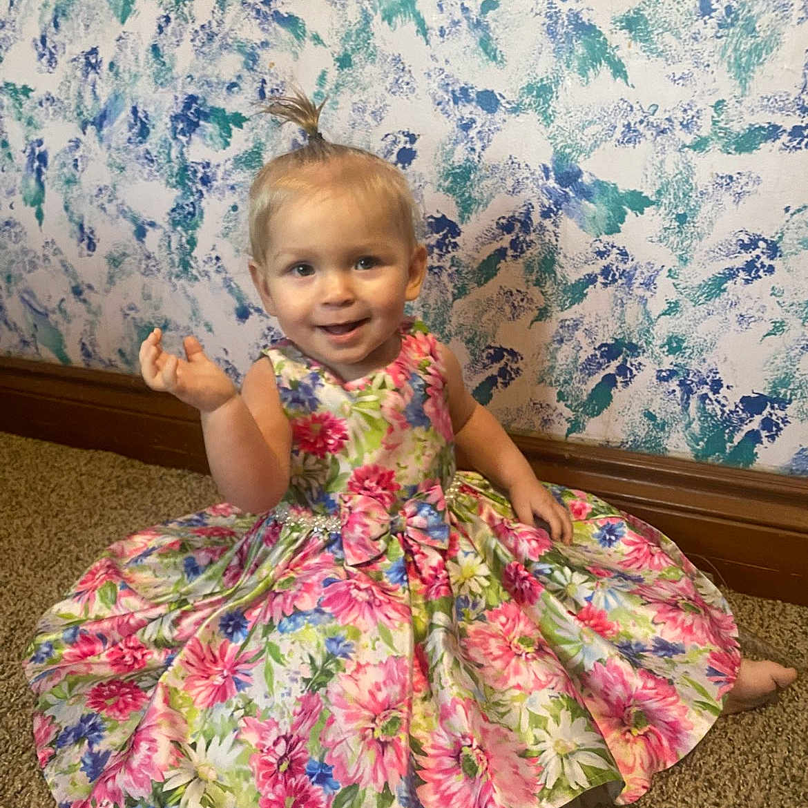 Zoey joined the competition — help win amazing prizes! toddler, child, smiling, dress, floral_pattern, carpet, indoor, wallpaper, colorful, happy, sitting, person, baby, hair_tie, cute, floor, portrait, young_child, casual, playful