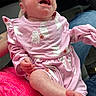 baby, newborn, child, crying, open_mouth, face, portrait, pink_clothing, ghost_pattern, halloween, onesie, dress, sitting, infant, foot, hand, car, lap, indoor, close_up