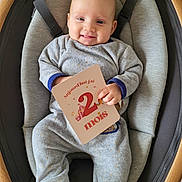 Maëlle a rejoint le concours — aidez-le/la à gagner de superbes lots ! baby, infant, smiling, milestone_card, clothing, pajamas, baby_seat, cushion, face, hand, wooden_frame, comfort, indoor, cute, child, person, newborn, happy, sitting, portrait