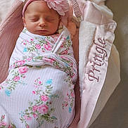 Elianna is registered to the contest to win money with this photo: newborn, baby, swaddled, flower_headband, sleeping, basket, blanket, pink, floral, cozy, soft, cute, infant, portrait, indoors, resting, peaceful, fabric, toddler, head