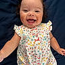 Emilia Rose is registered to the contest to win money with this photo: baby, blanket, blue_background, cheerful, child, curly_hair, cute, dress, face, floral_pattern, happy, indoors, infant, lying_down, person, portrait, skin, sleeveless, smiling, young