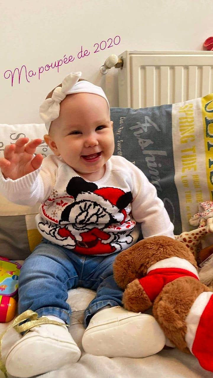 Mila a rejoint le concours — aidez-le/la à gagner de superbes lots ! baby, baby_laughing, baby_toddler_clothing, baby_toys, bed_frame, child, hair_accessory, home_accessories, joy, lap, laugh, linens, mouth, nose, person, plush, sitting, sock, stuffed_toy, textile