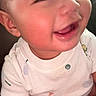 Zuuneil is registered to the contest to win money with this photo: baby, infant, child, smiling, happy, close_up, portrait, face, eyes, cheeks, mouth, white_shirt, clothing, sitting, indoor, warm_lighting, couch, photography, cute, gummy_smile