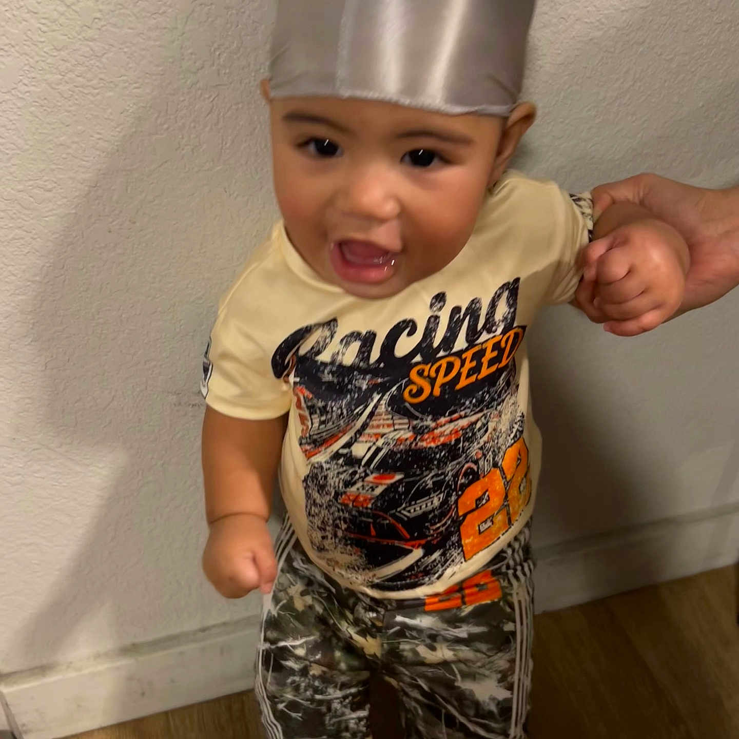 Zuuneil joined the competition — help win amazing prizes! baby, child, toddler, portrait, standing, smiling, indoors, hat, chef_hat, shirt, graphic_shirt, pants, shoes, adult_hand, hand_holding, wooden_floor, wall, home, fashion, candid