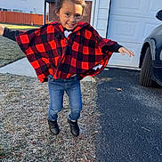 Isabella is registered to the contest to win money with this photo: black_boots, casual_clothing, child, daylight, driveway, fence, fun, garage, grass, hair_bun, happy, jeans, jumping, outdoor, person, playful, portrait, red_cape, smiling, young