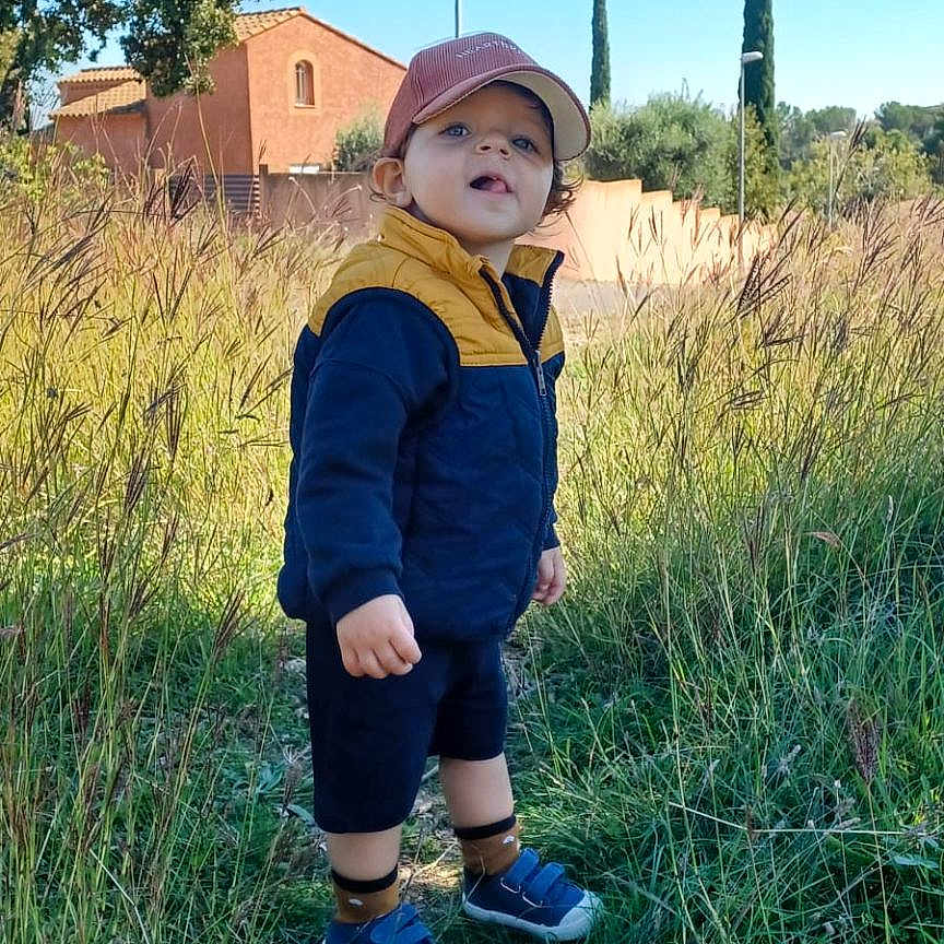 Klarence a rejoint le concours — aidez-le/la à gagner de superbes lots ! blue_sky, cap, child, curious, daylight, grass, jacket, nature, outdoor, path, person, plants, rural, shoes, shorts, smile, standing, sunny, toddler, trees