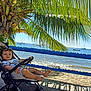 Klarence participe au concours pour gagner de l'argent avec cette photo : beach, blue_sky, boat, casual_clothing, child, fence, footwear, holiday, nature, ocean, outdoor, palm_tree, relaxing, sand, shade, stroller, summer, sunlight, toddler, vacation