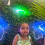 Skyler is registered to the contest to win money with this photo: bright, child, colorful, cute, decor, dress, face, fun, greenery, happy, indoor, lighting, neon_light, person, plant_wall, portrait, small_child, smiling, summer_clothing, toddler