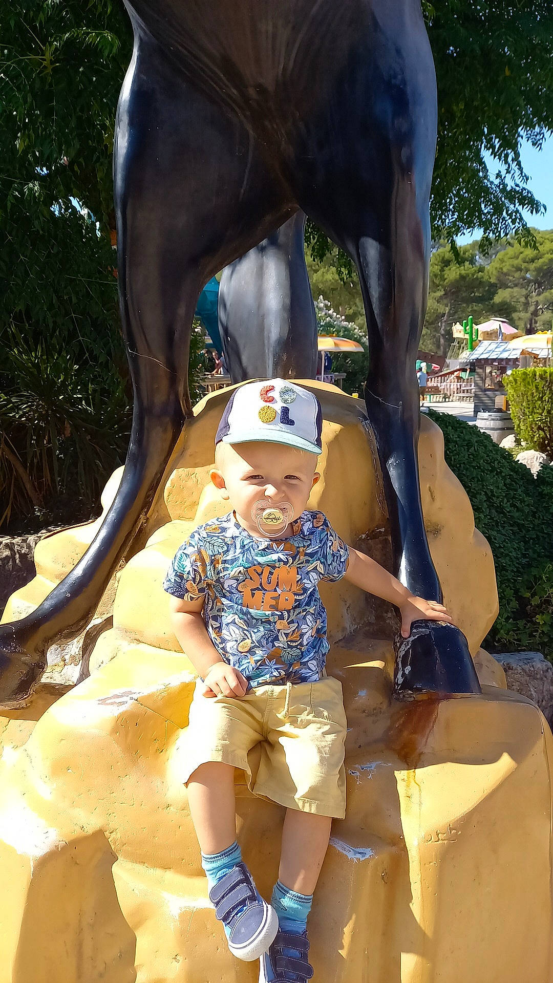 Luca participe au concours pour gagner de l'argent avec cette photo : child, elephant, fawn, fun, hat, headwear, indian_elephant, leisure, person, plant, recreation, shorts, snapshot, sun_hat, t_shirt, temple, terrestrial_animal, toddler, tree, vertebrate