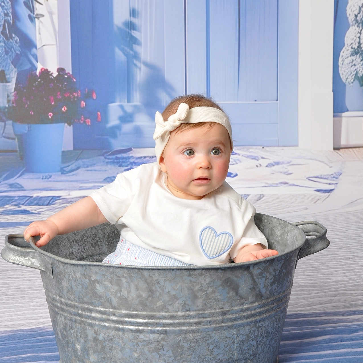 Hanae participe au concours pour gagner de l'argent avec cette photo : baby, child, tub, metal_tub, headband, blue_background, flower_pot, indoor, curious, sitting, white_shirt, heart_patch, portrait, infant, cute, decor, floor, hands, looking, studio_photo