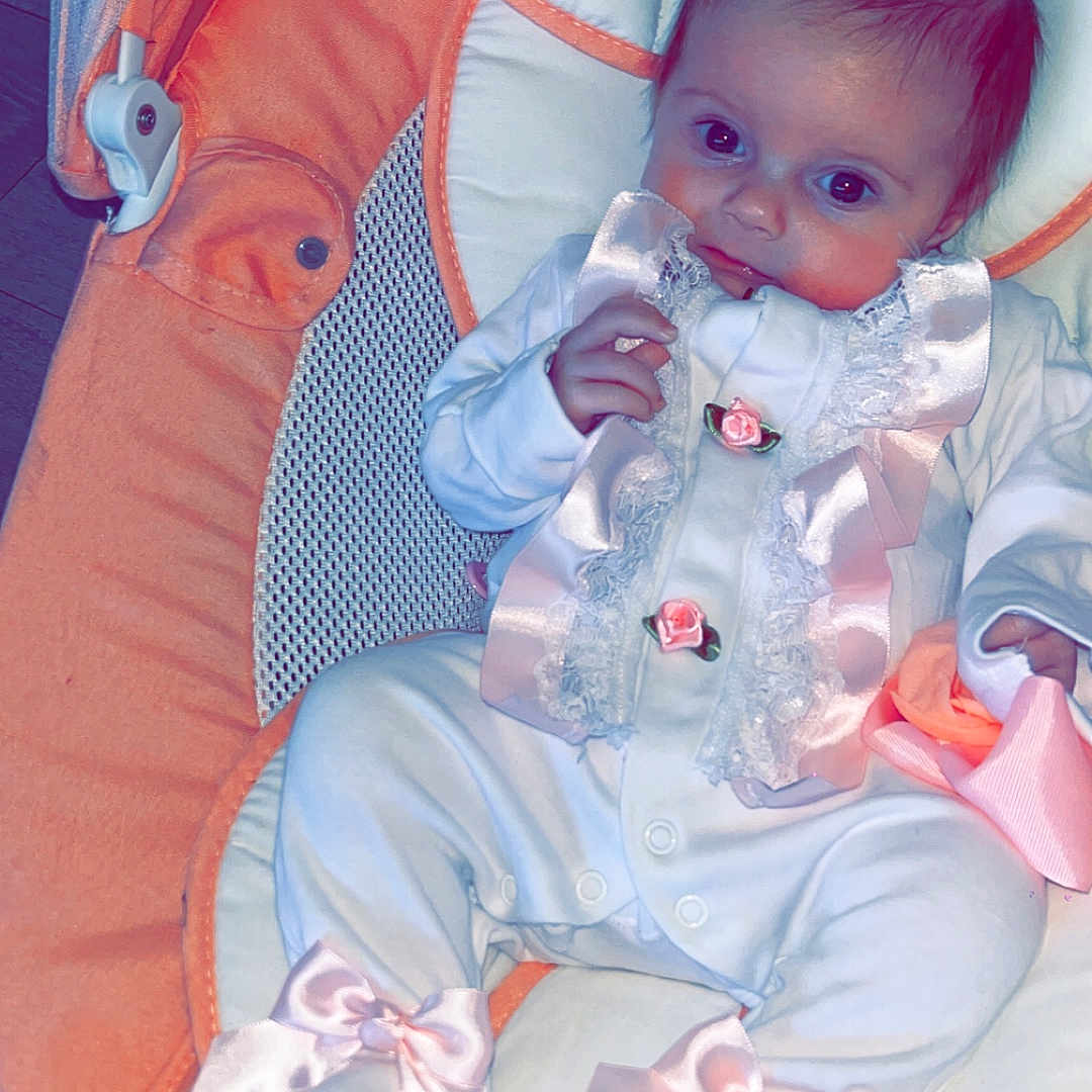 Ivy-Jayne is registered to the contest to win money with this photo: baby, baby_girl, baby_seat, child, clothing, cute, fabric, face, footwear, indoor, infant, lace, newborn, orange, pink_bows, portrait, ribbons, sitting, soft_toys, white