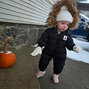 Keira joined the competition — help win amazing prizes! baby, beanie, building, candid, child, coat, cold_weather, curious, exploring, footwear, gloves, hood, outdoor, porch, pumpkin, sidewalk, snow, stone_wall, walking, winter_clothing