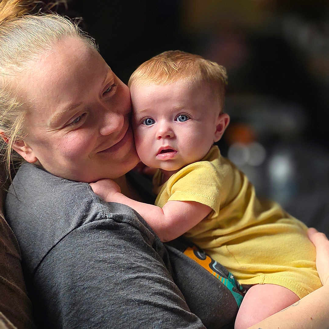 Aliyah joined the competition — help win amazing prizes! baby, adult, hug, love, affection, portrait, indoor, yellow_clothing, smile, curious, tattoo, short_hair, candid, family, child, person, closeup, comfort, casual, warmth