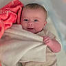 baby, blanket, bedding, infant, cute, smile, face, hand, clothing, lying_down, soft_texture, comfort, indoor, child, newborn, portrait, bed, cozy, pink, expression