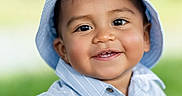 Dylan is registered to the contest to win money with this photo: child, toddler, portrait, smiling, happy, outdoor, sun_hat, striped_shirt, blue_clothing, short_sleeves, face, eyes, teeth, cheeks, brown_hair, greenery, blurred_background, daylight, closeup, photography