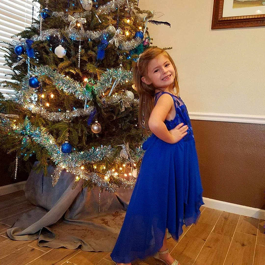 Claire is registered to the contest to win money with this photo: blue, christmas, christmas_decoration, christmas_eve, christmas_ornament, christmas_tree, clothing, cobalt_blue, cocktail_dress, dress, electric_blue, event, fir, formal_wear, gown, holiday, interior_design, joy, person, plant