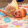 baby, smiling, blanket, colorful, cartoon, blue_balloon, carpet, indoor, happy, infant, toddler, playtime, cute, child, face, clothing, lying_down, soft_toys, home, fun