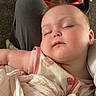 baby, sleeping, blanket, child, person, indoor, carpet, toy, tricycle, plush_toy, clothing, head, face, comfort, rest, nap, soft, cute, peaceful, lap