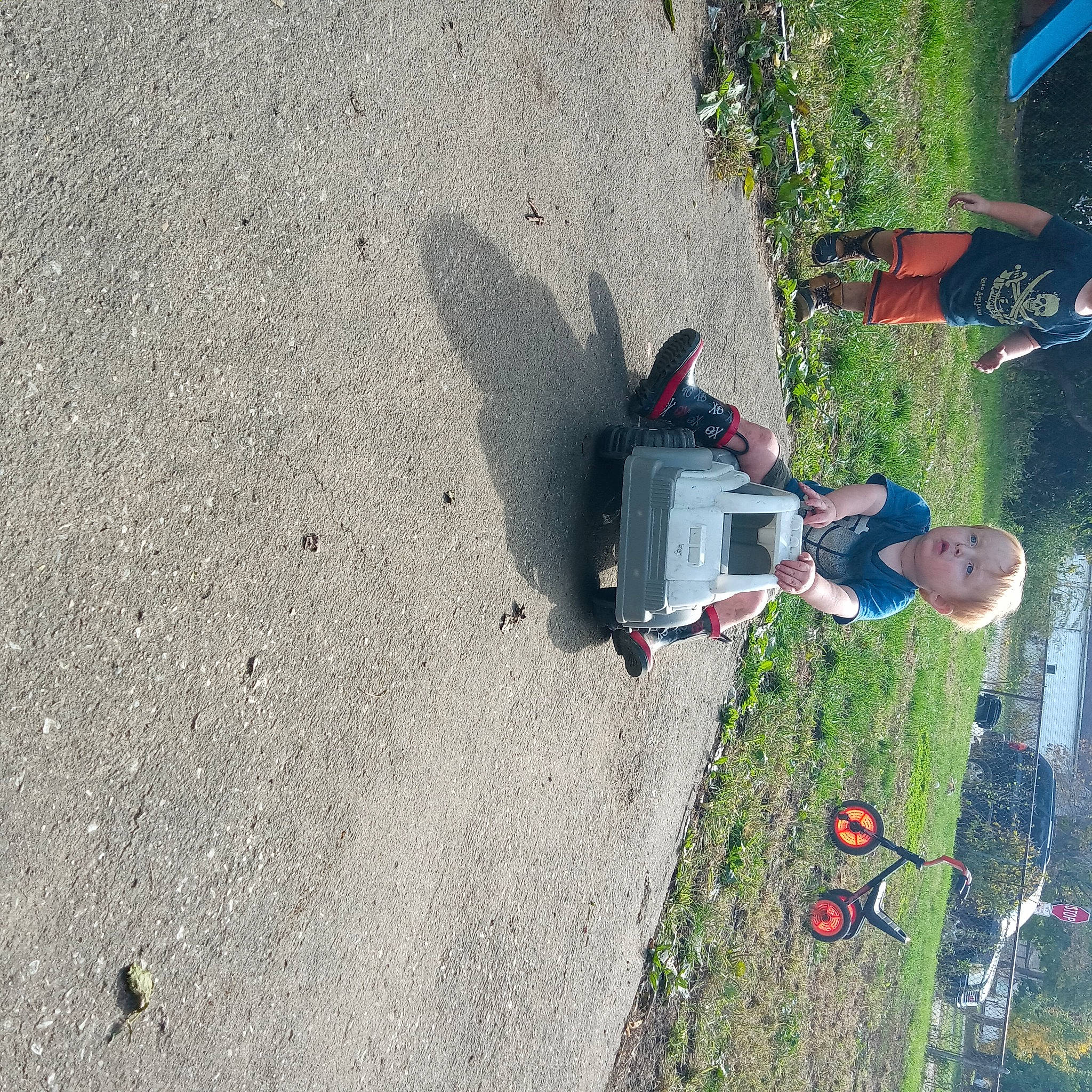 Clint is registered to the contest to win money with this photo: asphalt, car, concrete, grass, jeans, landscape, motor_vehicle, pedestrian, person, plant, recreation, road, road_surface, shadow, sidewalk, soil, tar, tire, tree, walking_shoe