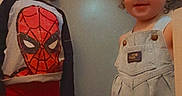 Alakai is registered to the contest to win money with this photo: toddler, child, indoor, door, carpet, clothing, spiderman, overalls, curly_hair, smile, barefoot, filter, devil_horns, playful, two_children, standing, young, cute, happy, kids