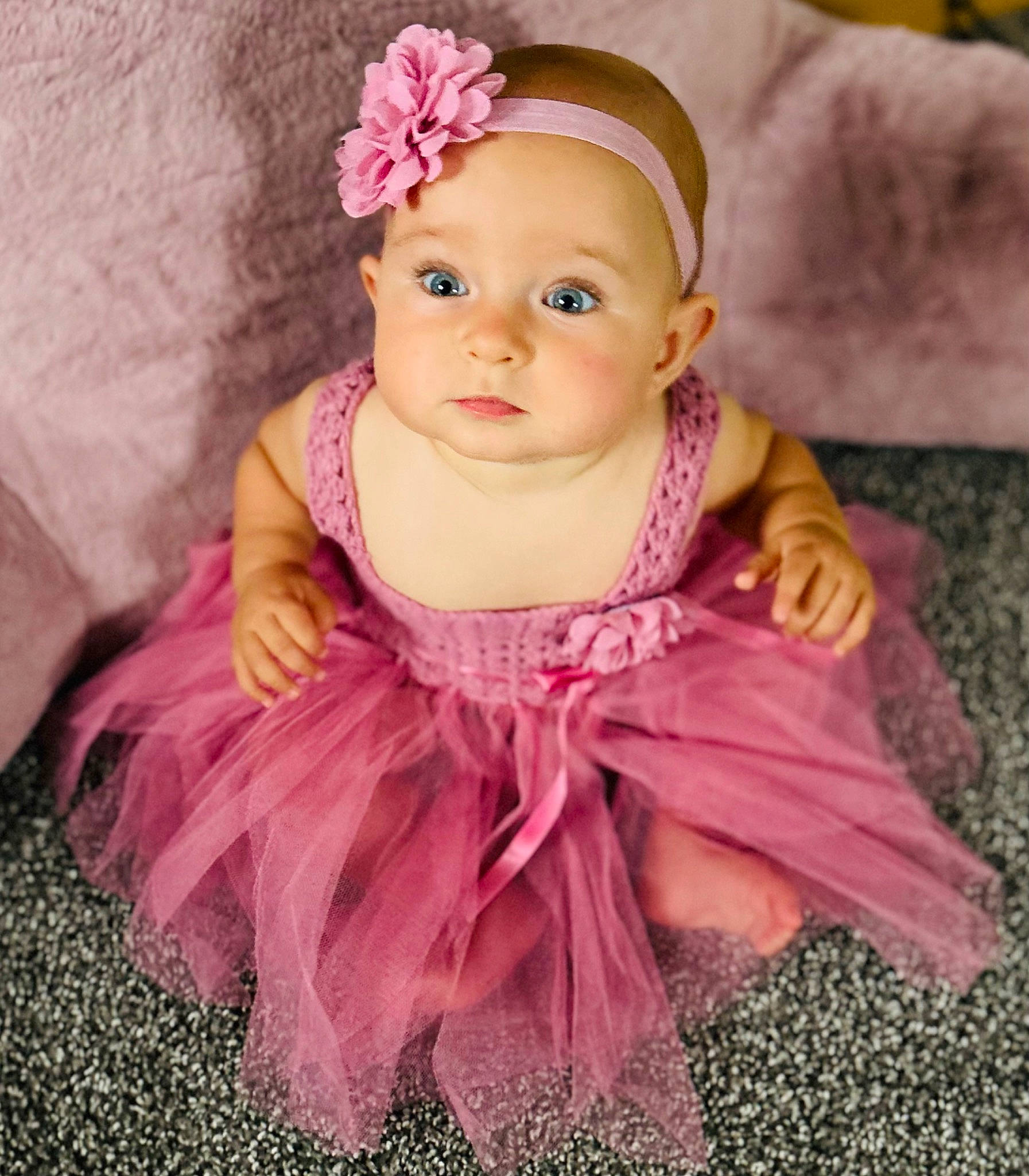 Anna is registered to the contest to win money with this photo: baby, baby_toddler_clothing, cap, cheek, child, dress, eye, face, hair_accessory, happy, headband, headpiece, headwear, lip, magenta, person, petal, pink, purple, skin