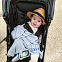 baby, stroller, hat, blue_blanket, handheld_device, floor, happy, smiling, indoor, person, child, clothing, seatbelt, knitted_blanket, headwear, footwear, baby_clothes, technology, portrait, infant