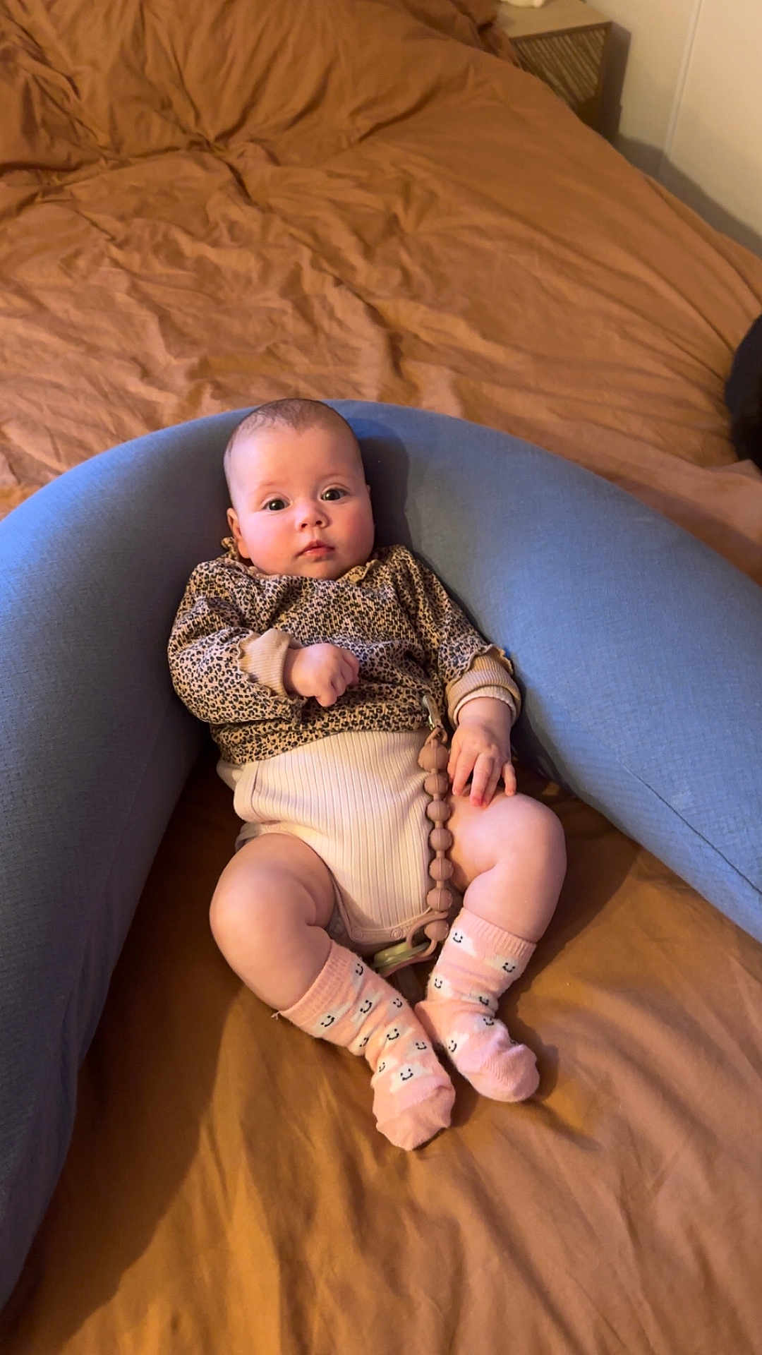 Mona a rejoint le concours — aidez-le/la à gagner de superbes lots ! baby, infant, child, bed, bedding, blue_pillow, nursing_pillow, onesie, socks, leopard_print, pacifier_clip, beads, portrait, indoor, cozy, hands, legs, skin, cute, gaze