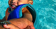 Chosyn is registered to the contest to win money with this photo: adult, arms, blue_water, child, face, happy, life_vest, outdoor, pool, portrait, recreation, red_float, safety, smiling, splash, summer, swimming, toddler, water, wet_hair