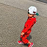 Chosyn is registered to the contest to win money with this photo: child, toddler, boy, outdoor, street, pavement, red_outfit, jumpsuit, hooded_jacket, baseball_cap, backwards_cap, sneakers, walking, standing, portrait, full_body, side_profile, fashion, sunlight, urban