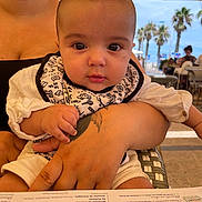 Zayn participe au concours pour gagner de l'argent avec cette photo : baby, child, person, arm, tattoo, hand, face, outdoor, restaurant, menu, table, umbrella, palm_tree, summer, clothing, bib, seat, adult, background, daylight