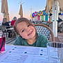 child, smiling, outdoor, cafe, table, drink, menu, glass, umbrella, evening, lights, happy, person, portrait, restaurant, seat, hair, face, clothing, necklace