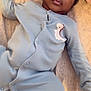 baby, infant, onesie, blue_clothing, dinosaur_patch, bed, blanket, towel, lying_down, face, curious, indoors, soft_lighting, young_child, portrait, relaxed, child, sleepwear, person, cute