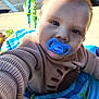 Finnigan is registered to the contest to win money with this photo: activity_seat, baby, child, closeup, colorful, cute, expression, face, hand, infant, outdoor, pacifier, parking_lot, person, play, portrait, seat, sunlight, sweater, toy