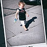 child, toddler, barefoot, sidewalk, sippy_cup, car, outdoor, sunny, shadow, polaroid_frame, casual_clothing, shorts, tank_top, concrete, daytime, walking, young_child, street, handwritten_date, playful