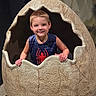 Jaxson is registered to the contest to win money with this photo: child, boy, smiling, dinosaur_egg, prop, cracked_egg, playful, indoor, portrait, short_hair, sleeveless_shirt, spider_emblem, blue_shirt, texture, imaginative, fun, cute, young, happy, posing