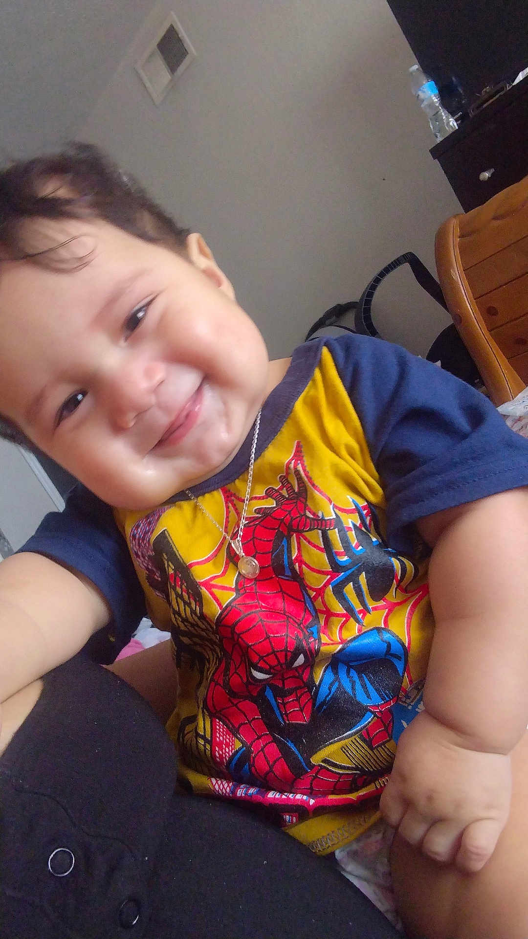 Liam joined the competition — help win amazing prizes! baby, child, smiling, indoor, tshirt, spiderman, necklace, furniture, chair, water_bottle, person, face, happy, cute, closeup, hand, sitting, skin, hair, room