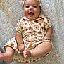 baby, smiling, floral_outfit, headband, barefoot, patterned_blanket, happy, infant, cute, child, portrait, lying_down, kicking, indoors, soft_lighting, cheerful, closeup, skin, person, joy