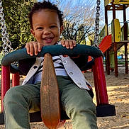 éden participe au concours pour gagner de l'argent avec cette photo : child, toddler, swing, playground, smiling, happy, outdoor, daylight, trees, play_structure, sand, clothing, shoes, grass, fun, park, person, holding, joy, recreation