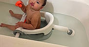 Nova Rose joined the competition — help win amazing prizes! baby, bathtub, bath_seat, child, toy, water, bathroom, tiles, funny_face, curly_hair, sitting, naked, infant, cute, expression, playing, indoor, person, bath_time, orange_toy