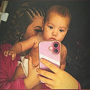 Nova Rose joined the competition — help win amazing prizes! baby, person, selfie, smartphone, hand, braided_hair, robe, indoor, portrait, child, skin, face, holding, curly_hair, diaper, closeup, expression, technology, phone_case, warm_lighting