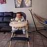 baby, child, high_chair, smiling, tongue_out, indoors, living_room, sofa, hammock, angel_wings, wall_art, tiled_floor, furniture, seated, infant, striped_clothing, socks, portrait, home, happy