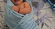 Brayden Smith joined the competition — help win amazing prizes! baby, infant, child, portrait, lying_down, swaddled, blanket, blue_blanket, bed, bedspread, floral_pattern, home, indoor, face, eyes_open, open_mouth, hand, adult_hand, cozy, colorful