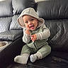 baby, child, infant, smiling, laughing, tongue_out, thumbs_up, hooded_outfit, green_clothing, sitting, couch, leather_couch, indoor, portrait, happy, cute, socks, zipper, quilted, vehicle_interior