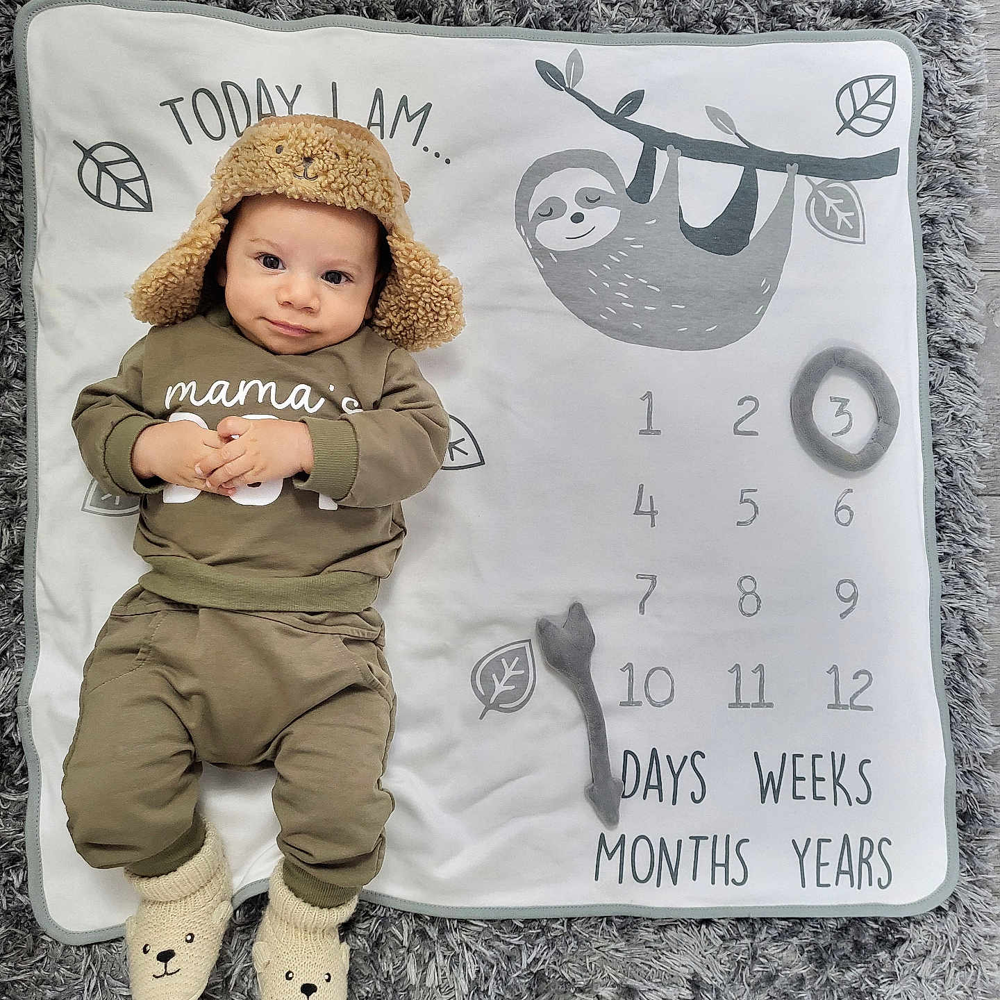 Asher is registered to the contest to win money with this photo: baby, bonnet, cap, clothing, face, hat, head, homedecor, hood, hosiery, number, pants, person, photography, portrait, sitting, sock, symbol, tape, text
