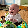 activity_center, baby, baby_toy, child, clothing, colorful, cute, expression, floor, hand, happy, head, indoor, infant, person, playful, room, seat, smiling, toy