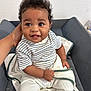 Jahed a rejoint le concours — aidez-le/la à gagner de superbes lots ! baby, child, smiling, striped_shirt, white_pants, curly_hair, cushion, changing_pad, hand, indoor, person, happy, towel, seated, infant, cute, skin, face, eyes, young